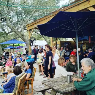Guests gathered under umbrellas and oak trees in The Courtyard at The Point Restaurant Perdido
