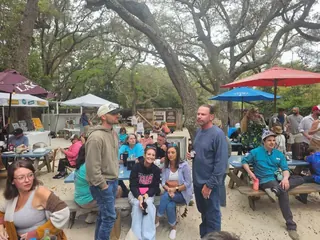 Crowd at picnic tables under the live oaks during a festival at The Point Restaurant Perdido, FL